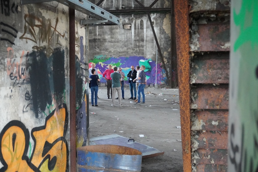 Auf diesem Bild sehen Sie eine Gruppe CDU-Ratsmitglieder aus einiger Entfernung in einer ehemaligen Werkshalle stehen.